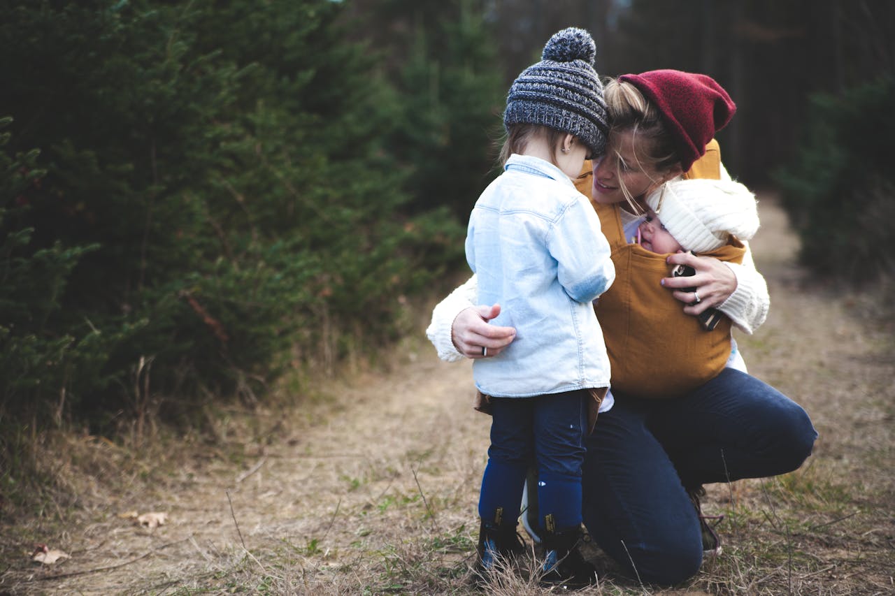 A loving mother with her two children exploring a forest path during the day.